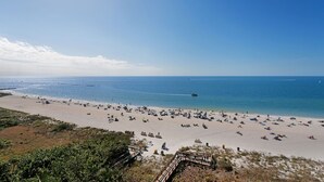 Une plage avec une promenade en bois menant à la rive, une plage de sable et l’océan en arrière-plan.