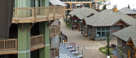 A resort with multiple buildings, including a prominent green structure with a balcony and a central building with a ski lift visible in the background.