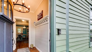 A hallway with a chandelier, a welcome sign, and a door leading to a dining area. - Red Lodge Home on Broadway - 15 Min to Ski Resort! (Red Lodge)
