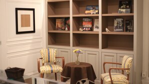 A room with a bookshelf, two patterned chairs, a small table with a vase, and a framed picture on the wall. - 3 bedrooms Premium Apartment - La Suite Lanterne (Lyon)