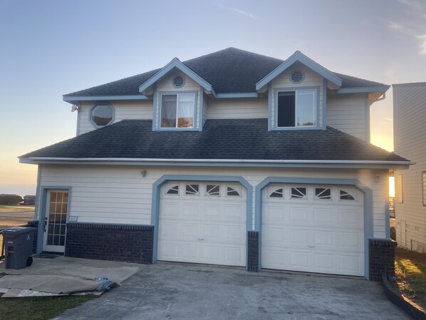 A two-story house with a garage, a brick foundation, and a clear sky.