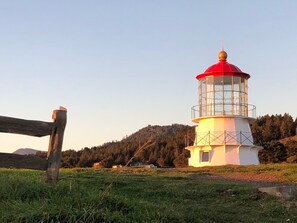 A lighthouse with a red top, white body, and a glass enclosure.