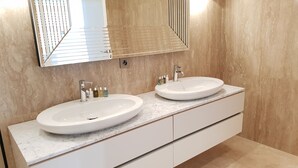 Un baño moderno con dos lavamanos, un espejo grande y encimera de mármol.