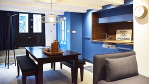 Une cuisine moderne avec des meubles bleus, une table à manger avec des bancs et une horloge au mur.