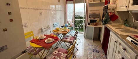 A compact kitchen with a dining area, featuring a small table set for two, a microwave, and a sink.