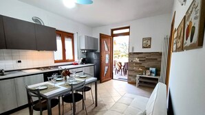 A modern kitchen with a dining area, a sofa, and a view of the outside.
