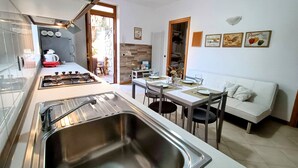A modern kitchen with a large sink, stove, and dining area with a white table and chairs.