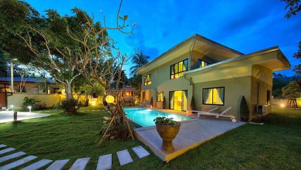 Una casa moderna de dos pisos con piscina, césped bien cuidado y un mirador.