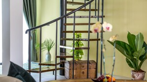 Una escalera con barandillas metálicas, un cofre de madera y plantas en macetas.