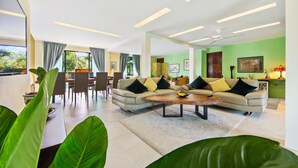 Una sala de estar moderna con un conjunto de sofás, comedor y ventanas amplias.