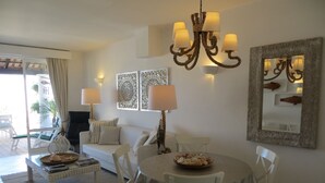 Una sala de estar con sofá, una mesa de comedor con sillas, una araña y lámparas de pared.