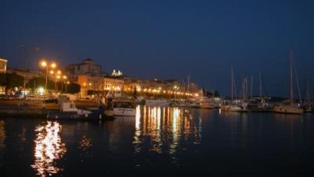 A marina at night with boats docked and buildings illuminated. - At the gates of Ortigia, apartment in historic building (Siracusa)