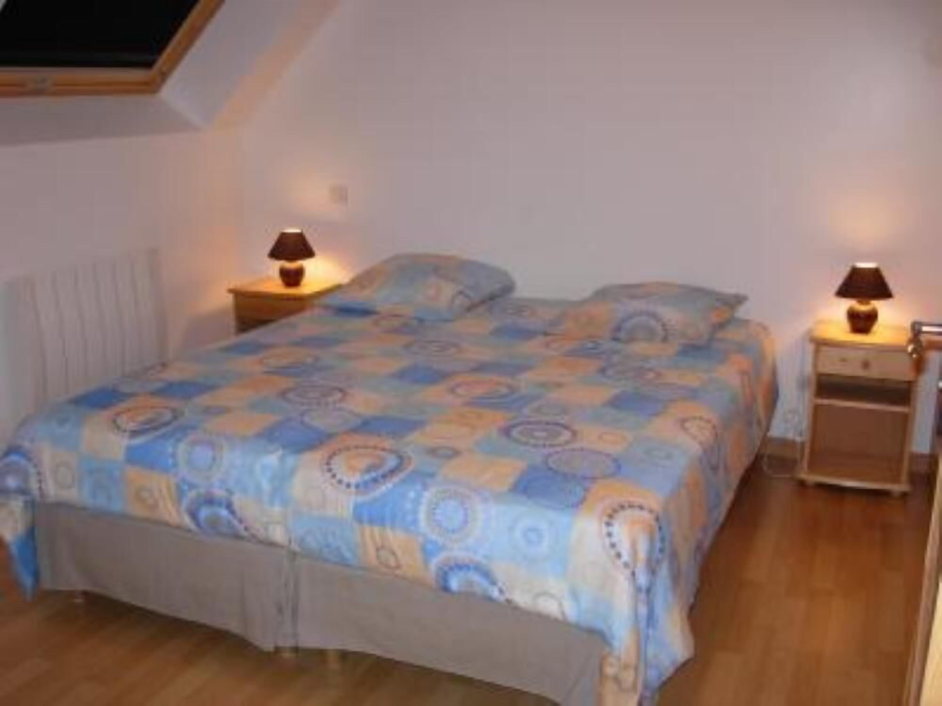 A bedroom with a bed, two bedside tables, and a window.