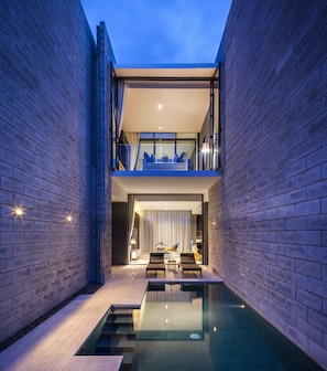 A modern building with a glass balcony, a pool, and a seating area. - Oceanphere Pattaya Villa (Sattahip)