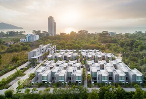 Ein moderner Wohnkomplex mit Rasterstruktur, umgeben von Grünflächen und Blick aufs Meer.