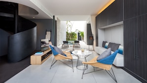 A modern living area with a curved staircase, a sofa set, a dining table, and a view of the outdoors. - Oceanphere Pattaya Villa (Sattahip)
