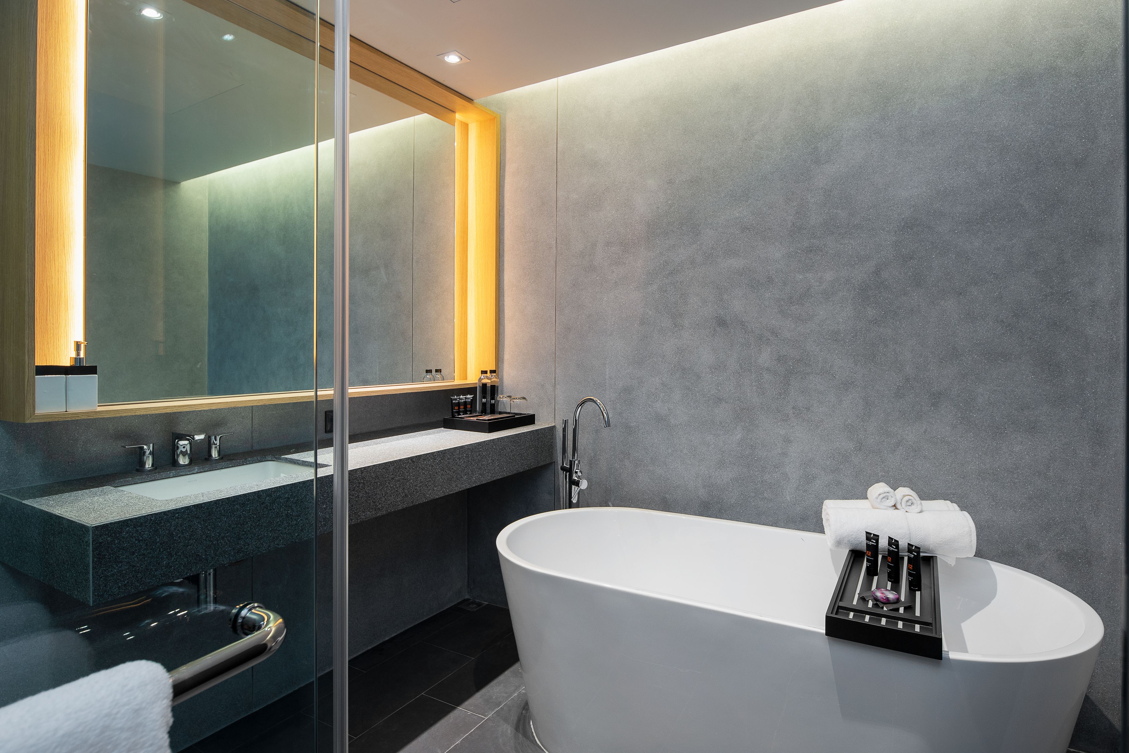 Un baño moderno con una bañera independiente, ducha con cerramiento de vidrio y tocador con un espejo grande.