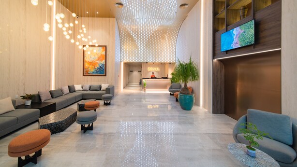 A modern lobby with a reception desk, seating area, and a large TV screen. - Zenia Boutique Hotel Nha Trang (Nha Trang)