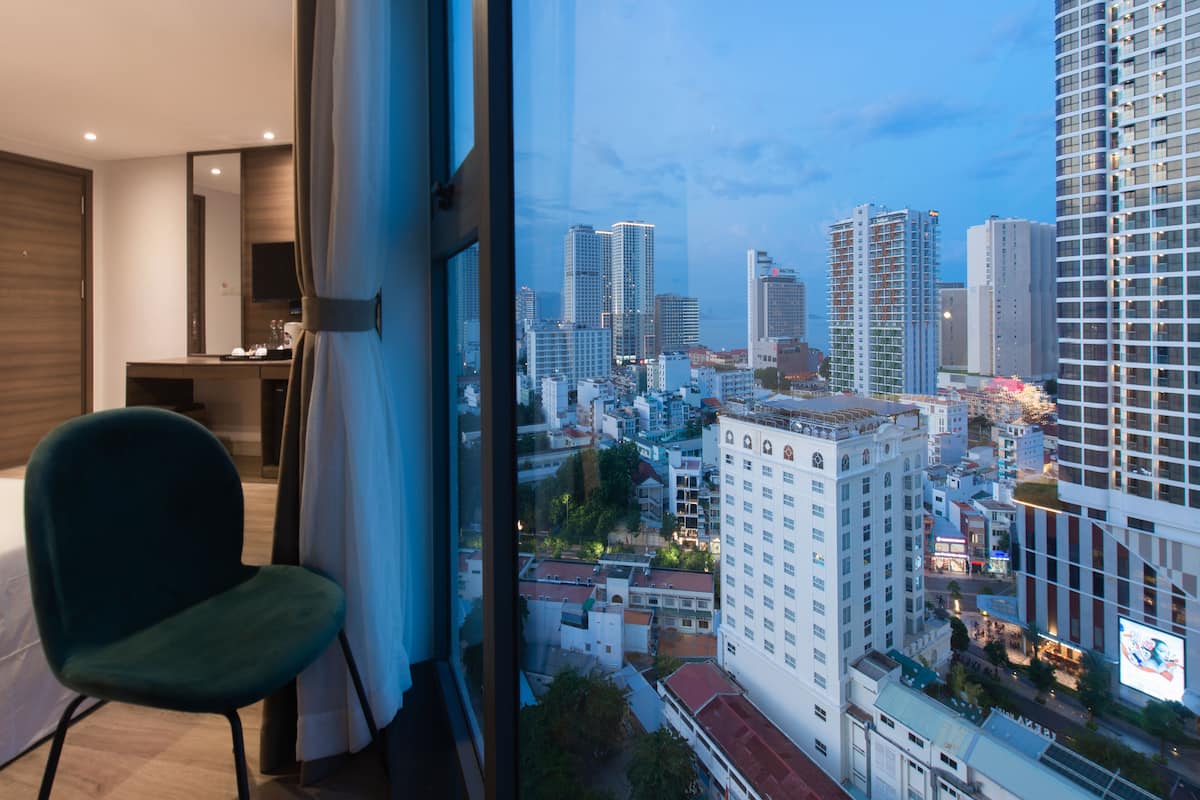 A modern hotel room with a large window offering a cityscape view.