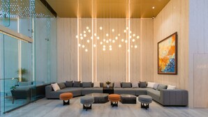 A modern living room with a sectional sofa, ottomans, a painting, and a unique ceiling light fixture.