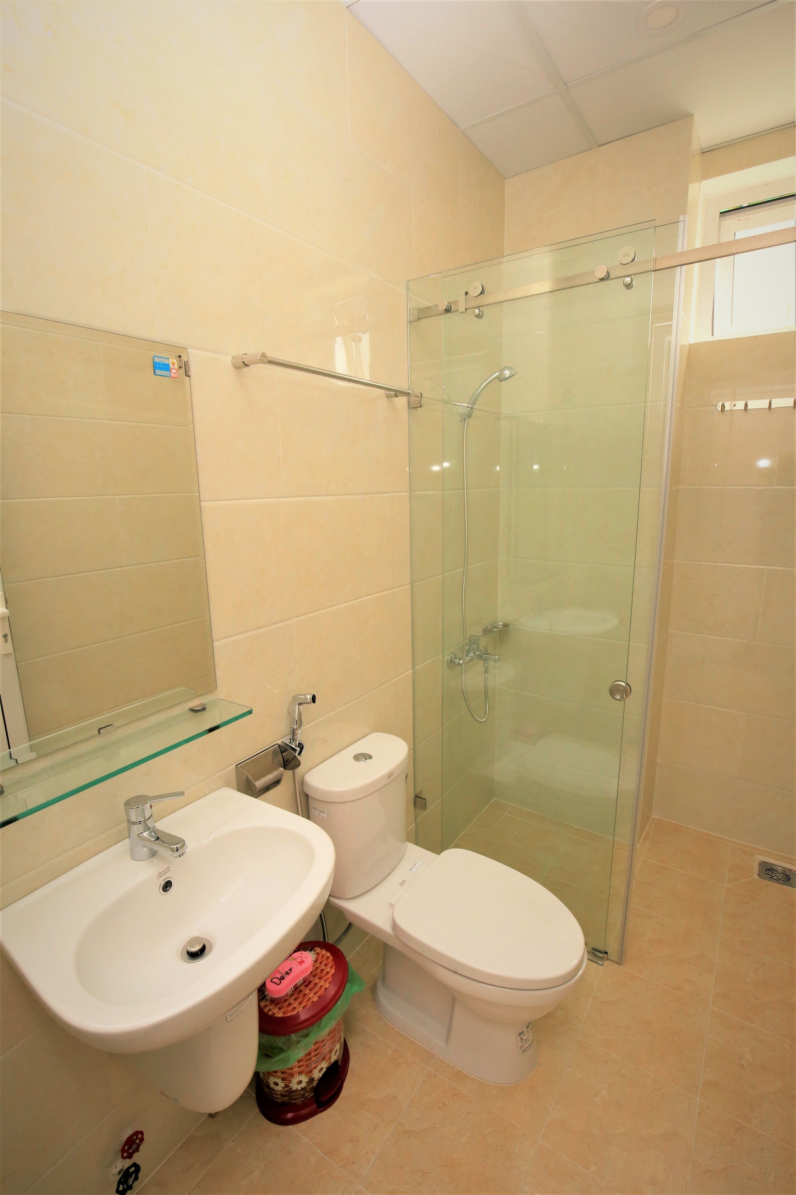 A bathroom with a glass shower enclosure, a white sink, and a toilet.