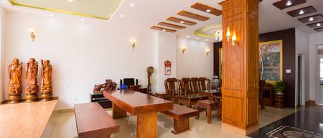 Una habitación amplia con una gran mesa de madera para comer, varias sillas y un pilar de madera.