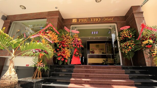 The entrance of the Phú Thọ Hotel with a staircase leading up to the entrance, decorated with floral arrangements and a red flag. - Da Lat Phu Tho Hotel (Xuan Huong - Da Lat)
