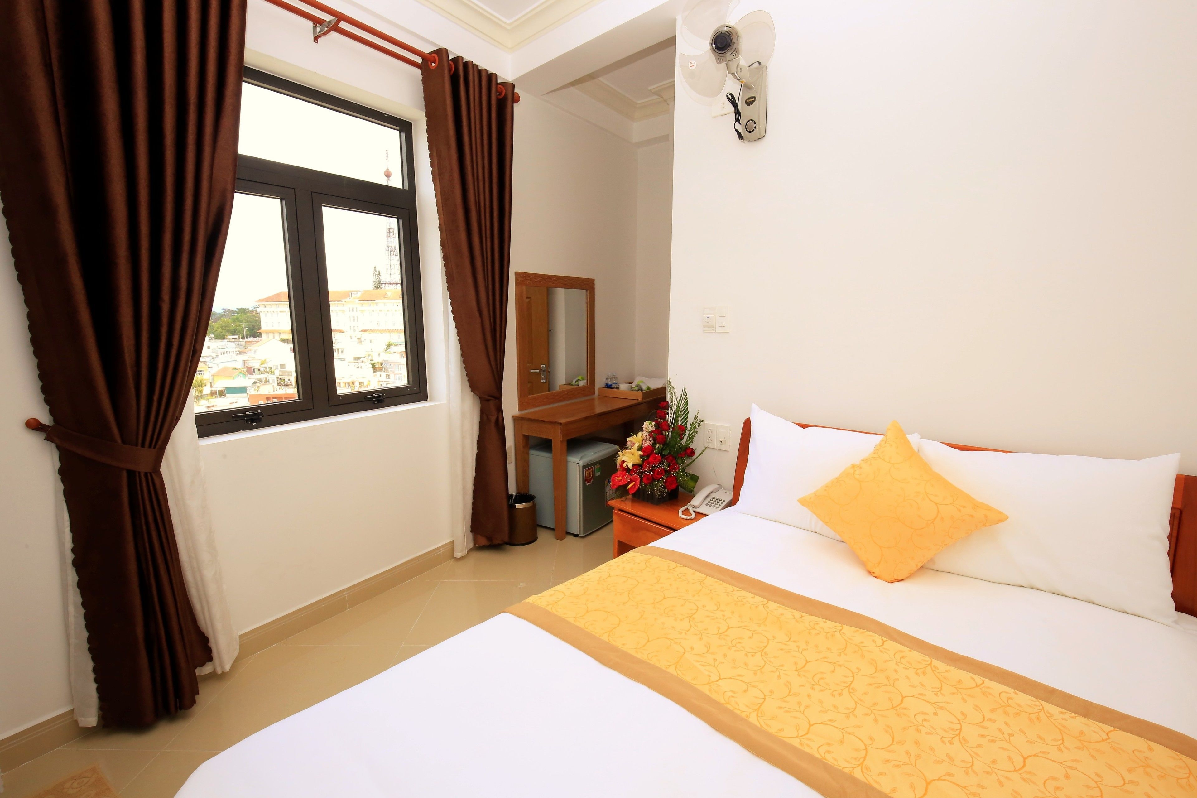 Una habitación de hotel con cama, escritorio, espejo y ventana con cortinas.