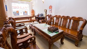 A traditional wooden furniture set including a sofa, chairs, and a table, with a visible clock and a framed picture on the wall. - Da Lat Phu Tho Hotel (Xuan Huong - Da Lat)