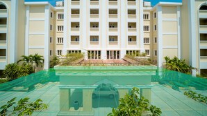 A multi-story hotel with a central courtyard, surrounded by lush greenery and a clear blue sky. - Hotel de la Renaissance (Siem Reap)