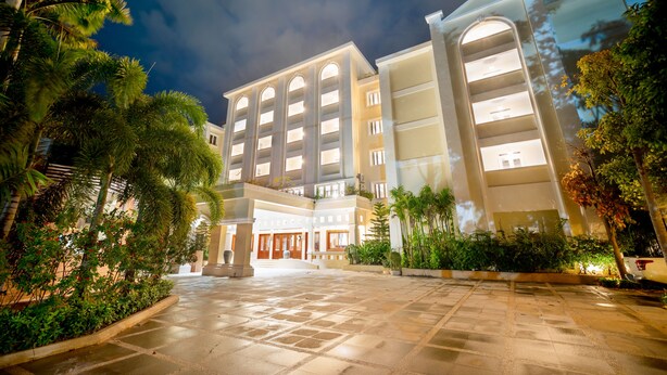 A multi-story hotel with a central courtyard, surrounded by lush greenery and palm trees. - Hotel de la Renaissance (Siem Reap)