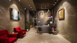Un área de recepción moderna con mostrador, sillas rojas y plantas en macetas.