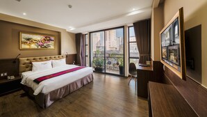 Habitación de hotel con una cama grande, un escritorio, una silla y un balcón con vistas a la ciudad.