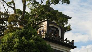 A building with a balcony and arched windows, surrounded by trees.