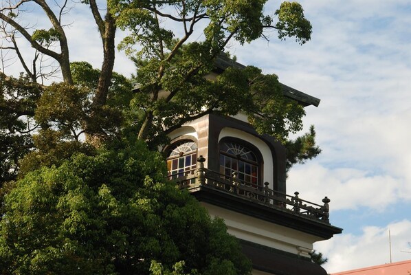 A building with a balcony and arched windows, surrounded by trees.