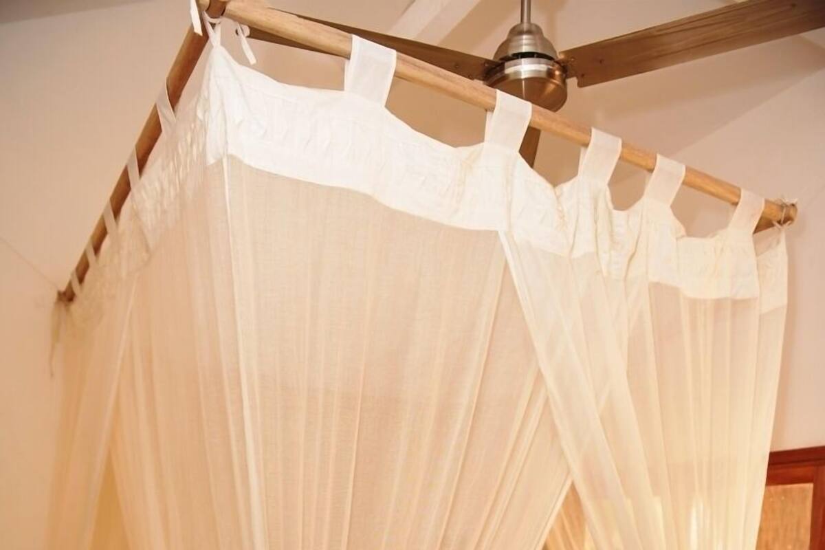 A bed with a canopy, wooden headboard, and a small bedside table.