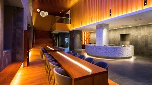 Eine moderne Hotelhalle mit einer langen Rezeption, einer Sitzecke und einer Treppe zu den oberen Etagen.
