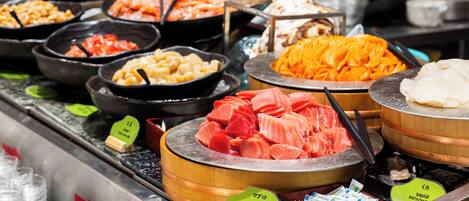 A variety of seafood displayed in wooden bowls with labels indicating types like tuna and squid.