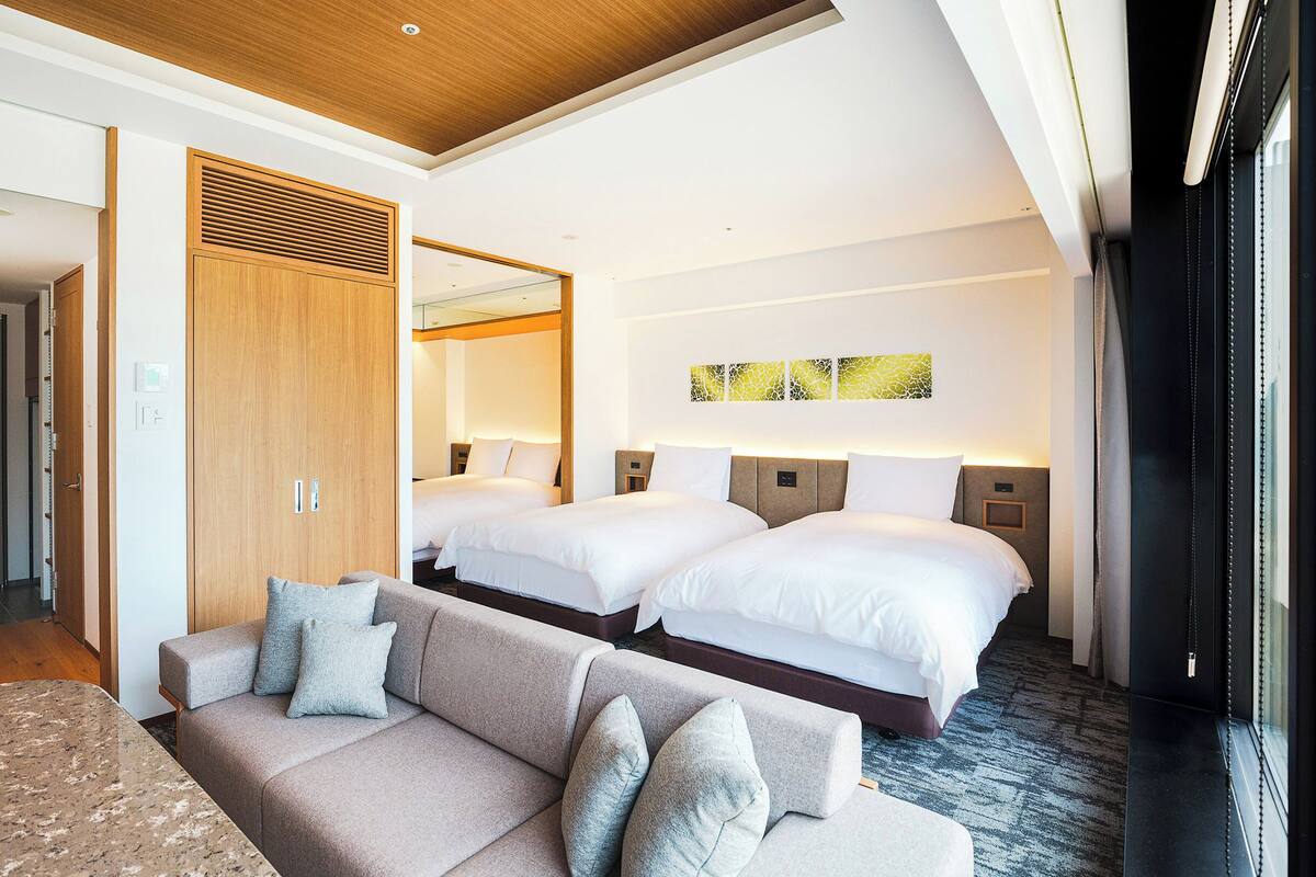 Une chambre d’hôtel avec deux lits, un canapé et une armoire en bois.
