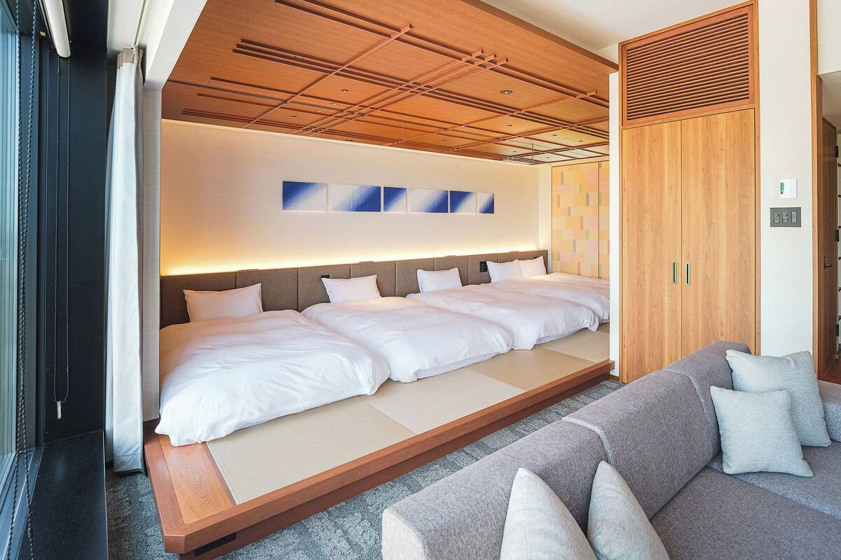 Une chambre d’hôtel avec un grand lit, un canapé et un décor en bois au plafond.