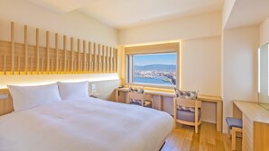 Ein Hotelzimmer mit einem großen Bett, einem Schreibtisch mit Stuhl, Blick auf die Stadt und einer Holzvertäfelung.