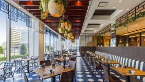 Ein modernes Restaurant mit hohen Decken, hängenden Pflanzen und einem Schachbrettmuster-Boden.