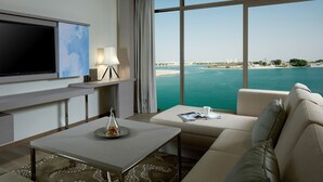 A modern hotel room with a large window offering a view of the sea and cityscape. - Royal M Hotel Abu Dhabi by Gewan (Abu Dhabi)