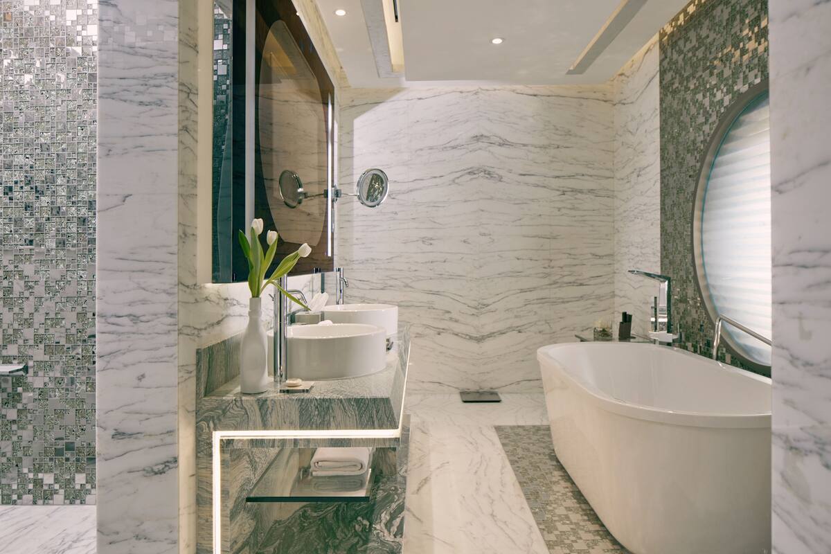 A modern bathroom with a freestanding bathtub, a vanity with two sinks, and a decorative mirror.