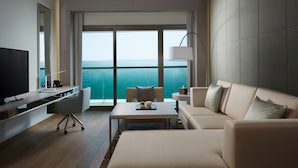 A modern hotel room with a large window, a flat-screen TV, a sofa, a coffee table, and a desk with a lamp. - Royal M Hotel Abu Dhabi by Gewan (Abu Dhabi)