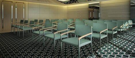 A conference room with rows of green chairs, a patterned carpet, and a ceiling with linear lighting fixtures.