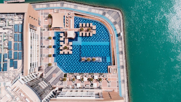 An aerial view of a resort with a large pool, sun loungers, and a beach area. - Royal M Hotel Abu Dhabi by Gewan (Abu Dhabi)