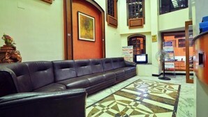 A lobby with a black leather sofa, a patterned floor, and a reception desk. - Hotel Naveen (Coimbatore)