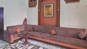 A living room with a brown sofa, a coffee table, and a patterned rug. - Hotel Naveen (Coimbatore)