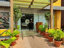 Una entrada moderna de edificio con puerta de vidrio, plantas en macetas y estructura de madera.